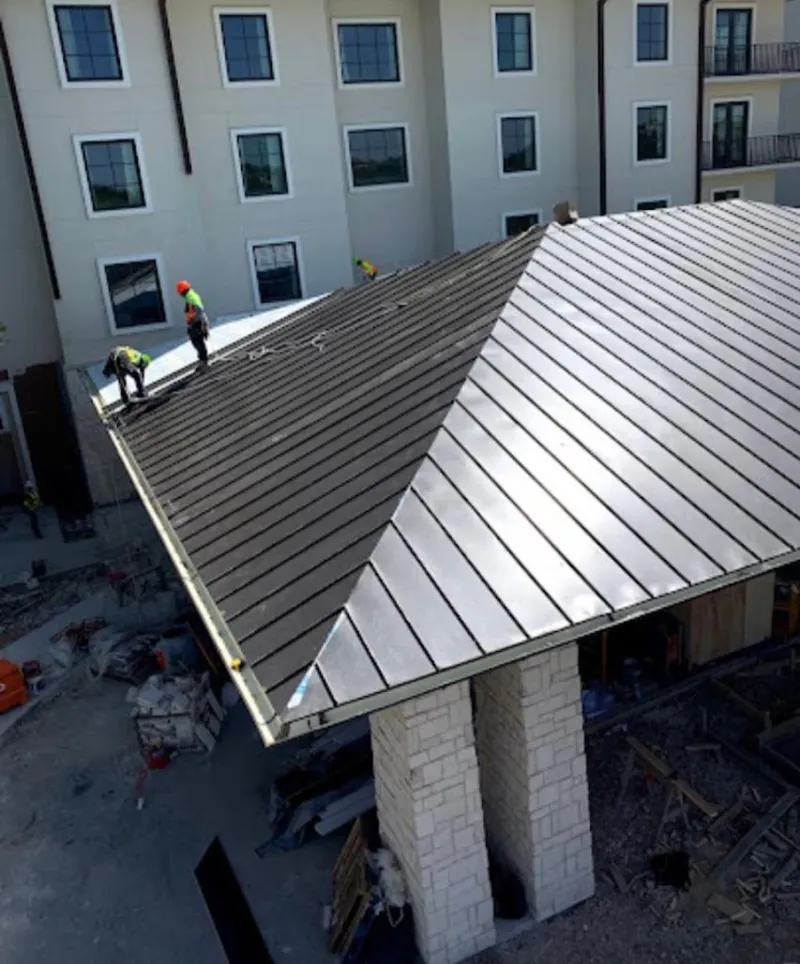 Crew installing standing seam metal roof panels on a commercial project in Lisbon